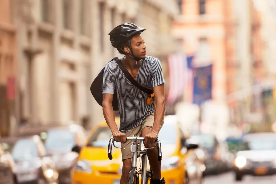 Man riding bicycle wearing black helmet on New York City street.